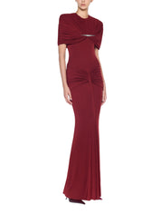 Form-fitting long dress featuring symmetrical draping at the bust and hips accented with a refined metal accessory